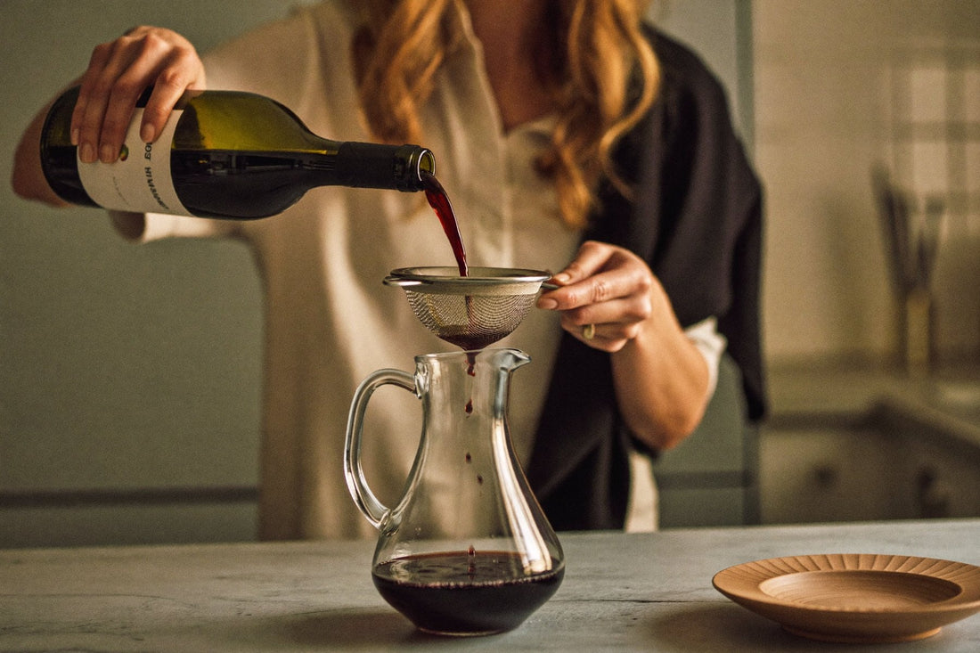 Wine being poured through a strainer into a carafe