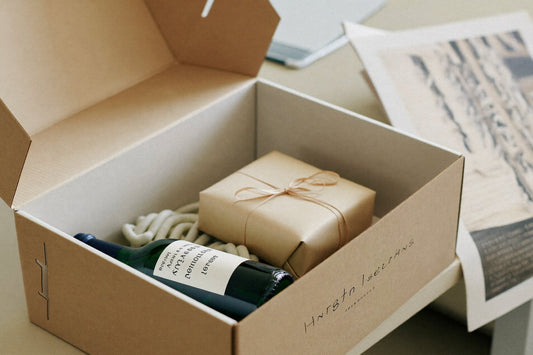 Opened gift box with a bottle of wine and a wrapped gift