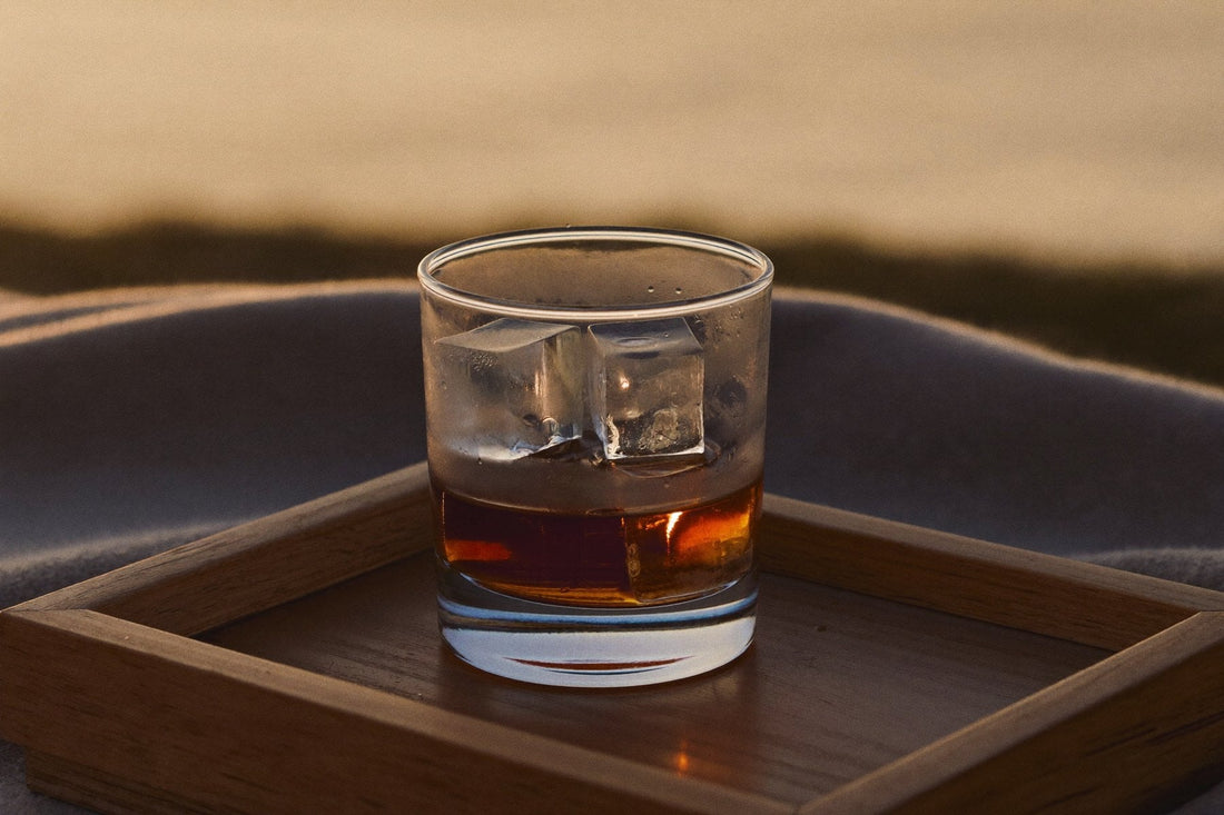 Glass with ice cubes on a wooden tray