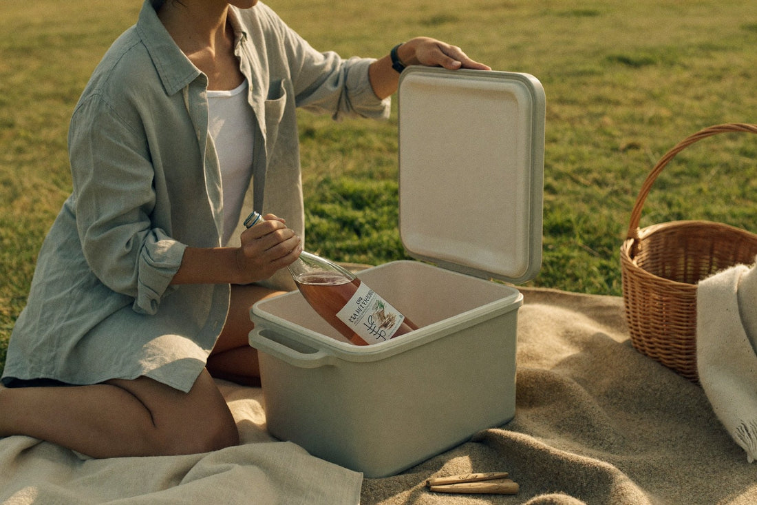 Woman lifting a bottle of rose from a cooler box at a picnic